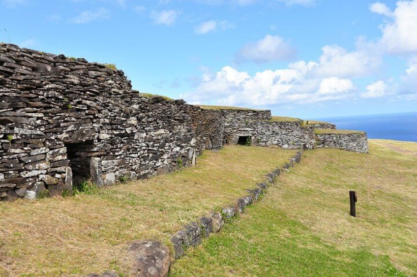 A stone wall structure with a grassy foreground and a clear sky. 2