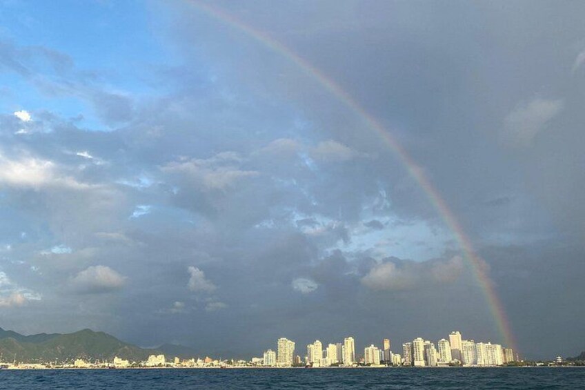 A city skyline with a rainbow over the water. 2