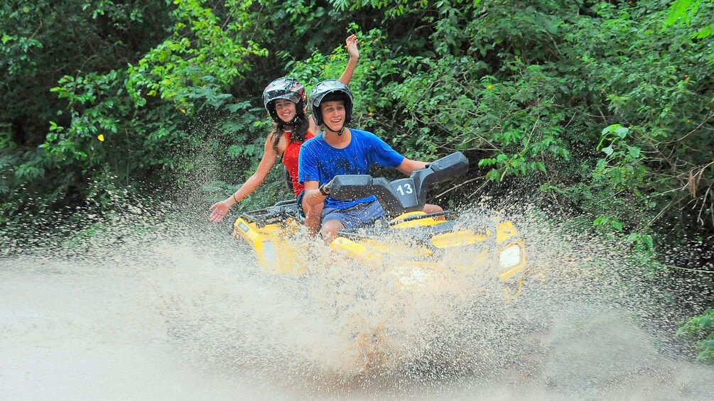 Couple riding on ATV through water in Cancun