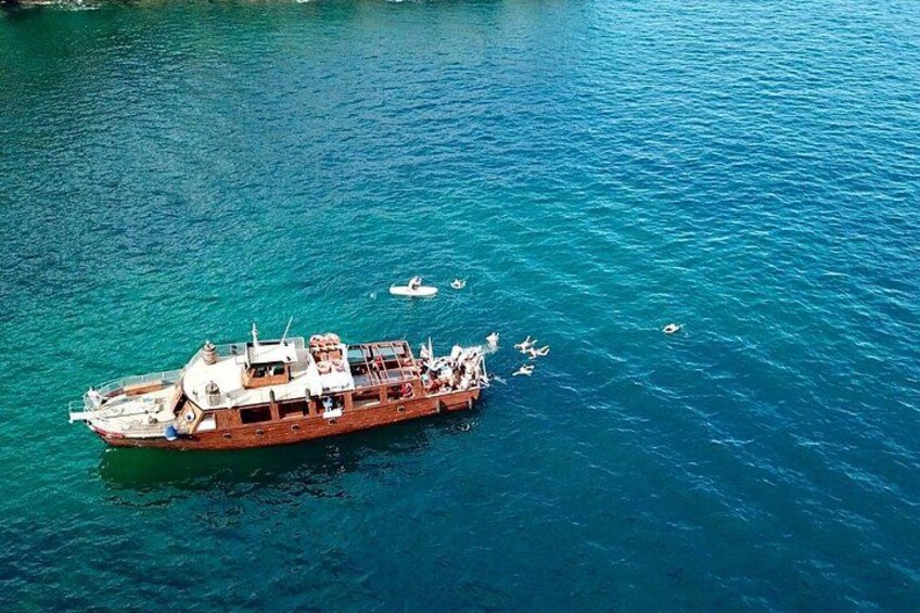 Een grote houten boot met passagiers op een rustige blauwe zee. 2