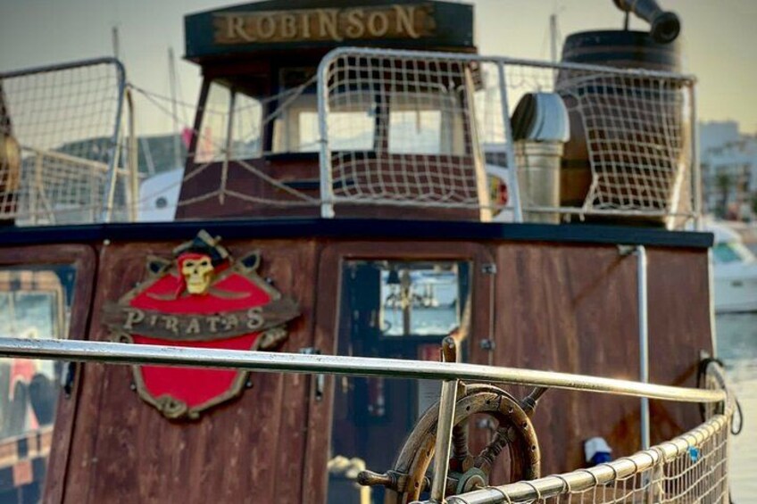 A wooden boat with a sign that reads 'Piratas' and a 'Robinson' sign above. 2