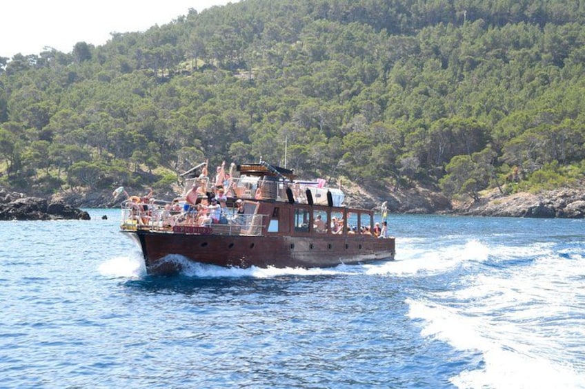 Een boot met passagiers op het water, omringd door een bebost kustgebied. 4