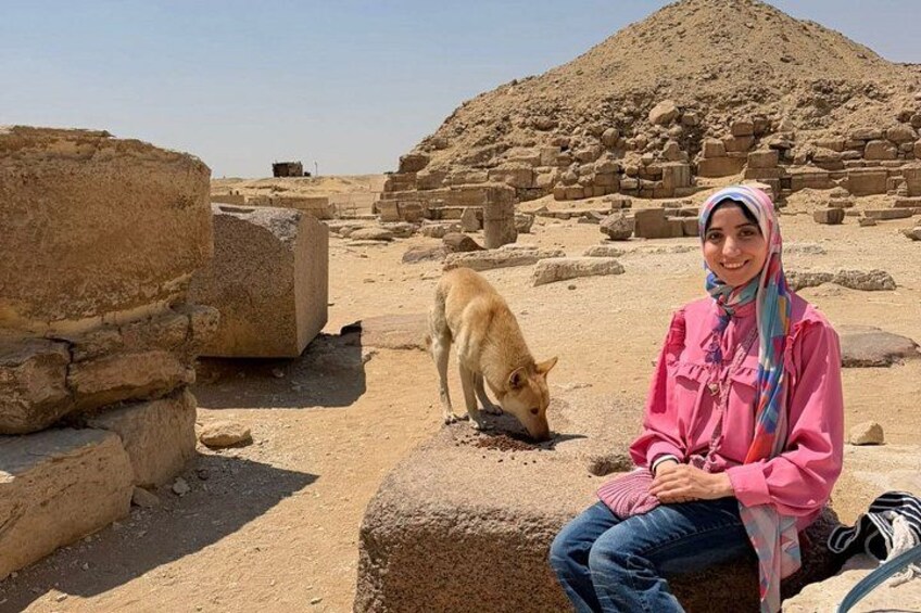 A person sitting on a stone block with a dog in an ancient ruin. 2