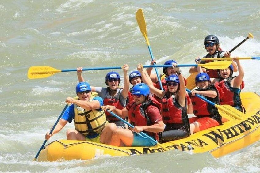 A group of people in a yellow raft with 'MONTANA WHITEWATER' written on it, paddling through water. 4