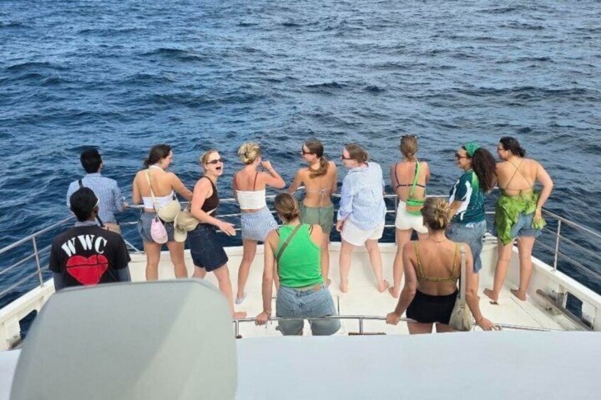 Un groupe de personnes se trouve sur un bateau, certaines d’entre elles portent des maillots de bain et regardent la mer. 5