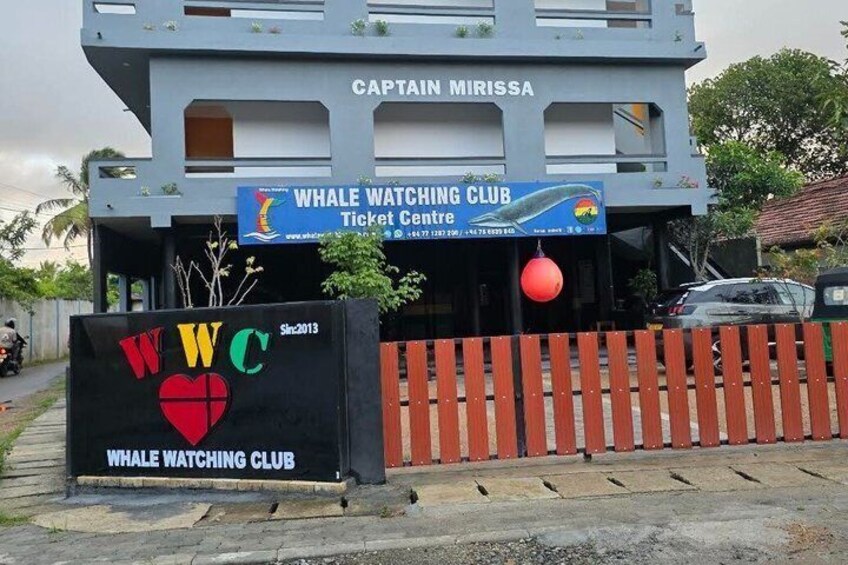 Un bâtiment sur lequel est apposée une enseigne indiquant le centre de vente de billets du club d’observation des baleines. 2
