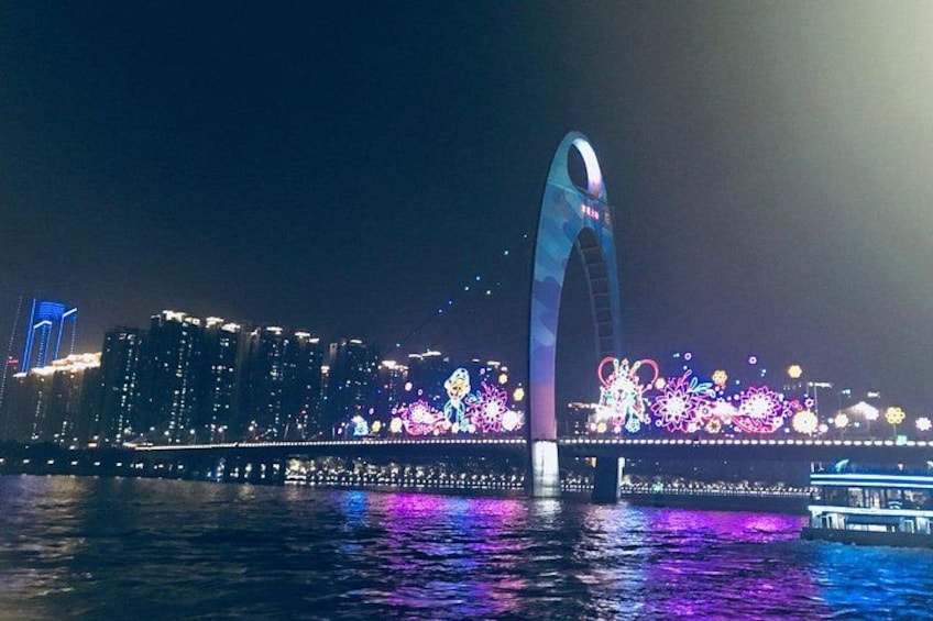 Eine hell erleuchtete Brücke mit einem markanten Bogen und farbenprächtigen Lichtern, die sich im Wasser spiegeln. 3