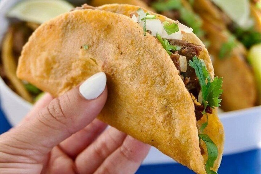 A hand holding a taco with visible fillings and a lime wedge. 3