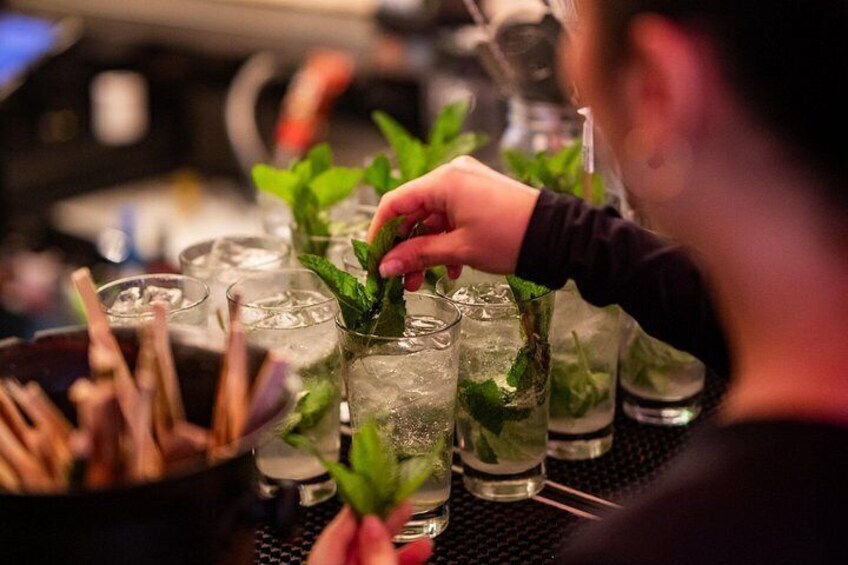 A person garnishing a drink with mint leaves. 2