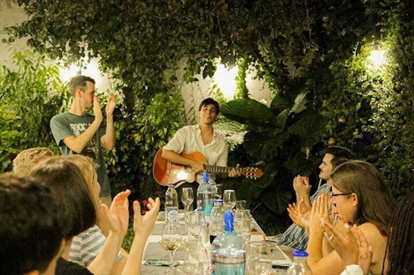Une personne joue de la guitare à une table, et les gens applaudissent. 3