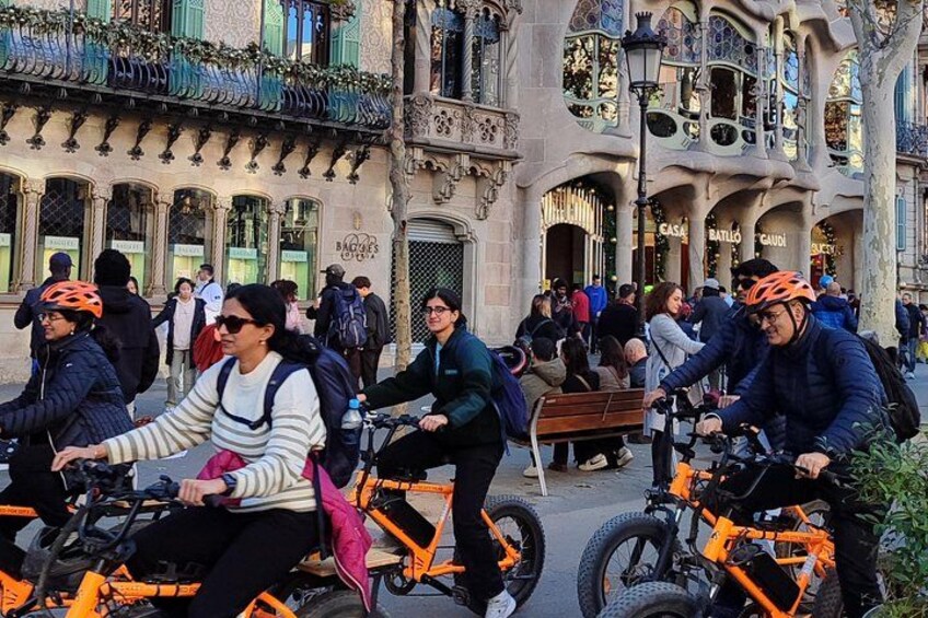 People riding bicycles on a street with ornate buildings in the background. 2