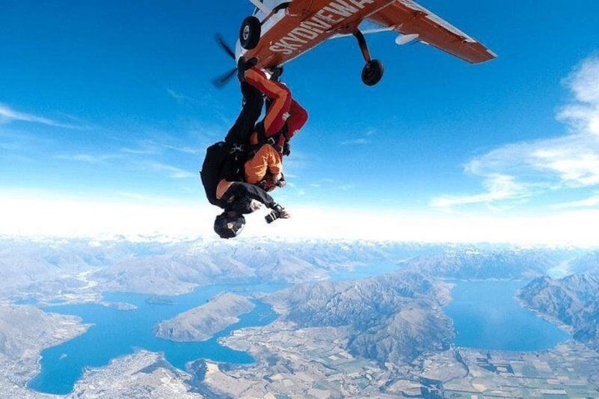 A person skydiving with a parachute, a mountainous landscape, and a body of water below. 3