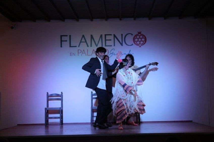 A stage with a man and a woman performing flamenco, a man in a suit, and a woman in a traditional flamenco dress. 5