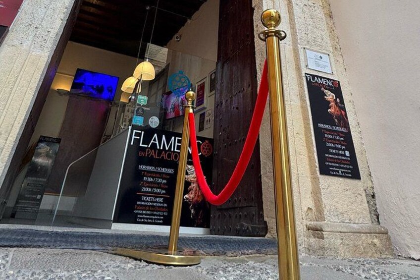 A red velvet rope barrier, a gold stanchion, and a sign for 'FLAMENGO & PALACIO' with event details. 2