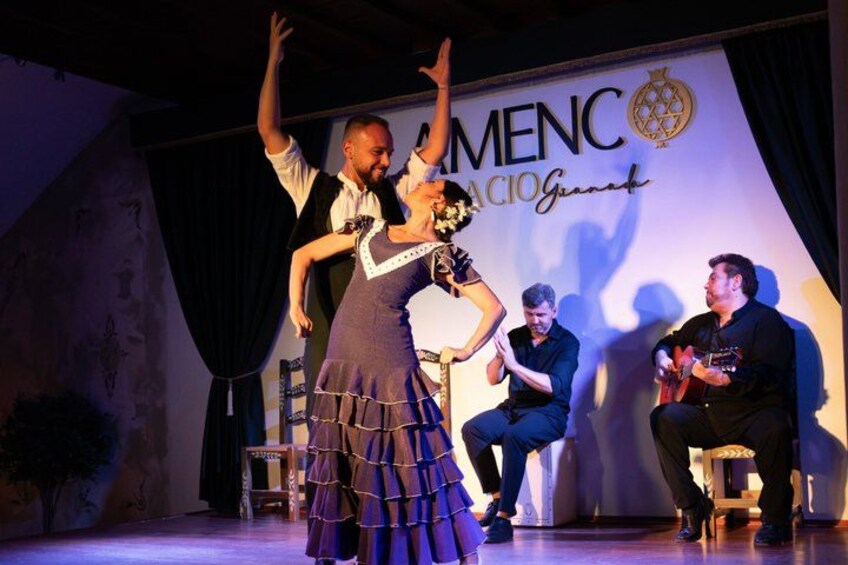 A stage with a couple performing, a man playing guitar, and a banner with 'MENC' text. 3
