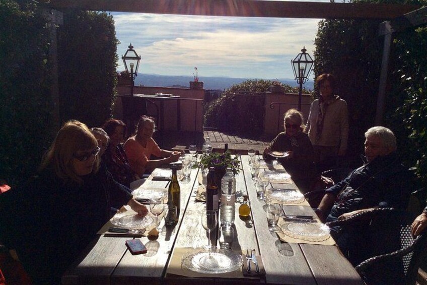 Eine Gruppe von Personen speist an einem hölzernen Tisch im Freien mit Blick auf die Landschaft. 5