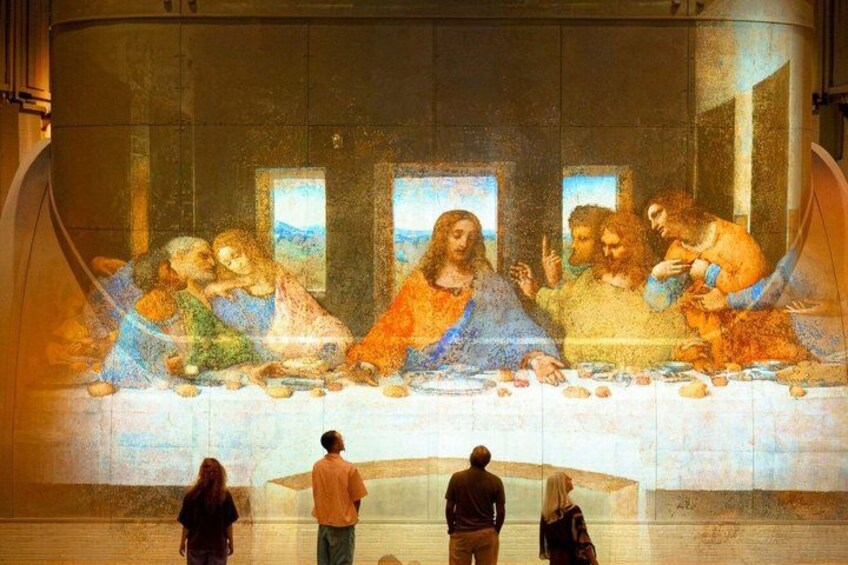 Een muurschildering van Het Laatste Avondmaal, afgebeeld met Jezus en zijn discipelen, en een aantal mensen die ernaar kijken. 2