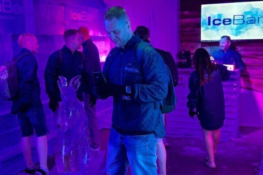 A person standing in a room with a large screen displaying 'IceBank' in the background. 2