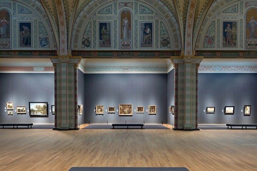 Ett konstgalleri med klassisk arkitektur, kännetecknat av kolonner och utsmyckade takdekorationer. 1