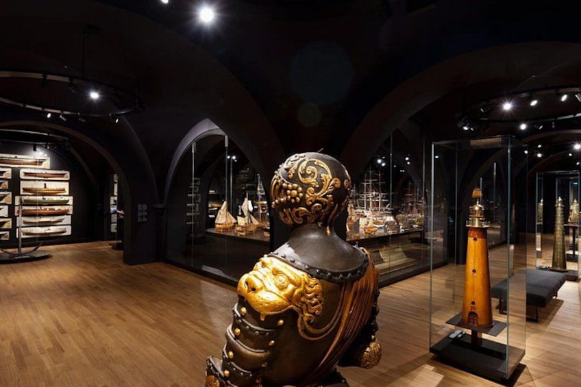 Un musée installé à l’intérieur d’un bâtiment, avec une statue dorée en pièce maîtresse, des vitrines contenant des objets d’art et un plancher en bois. 3