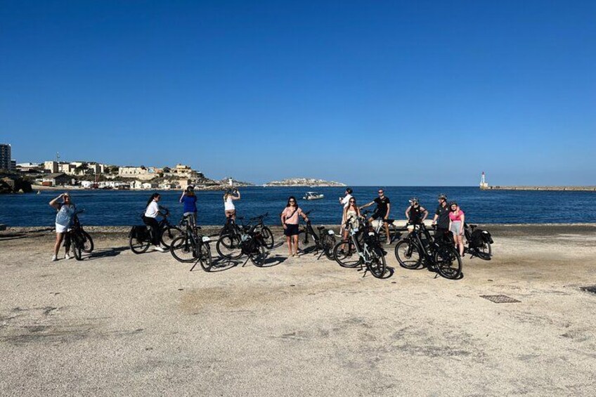 Un groupe de personnes à vélo se trouve près d’une zone côtière, avec un phare en arrière-plan. 3