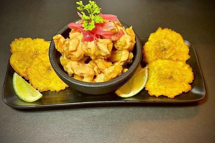 A bowl of food with fried plantains and lime wedges. 2