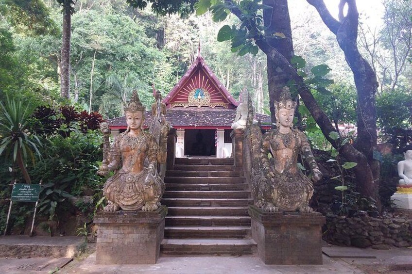 A temple with a red roof, two large statues, and a staircase leading to the entrance. 3