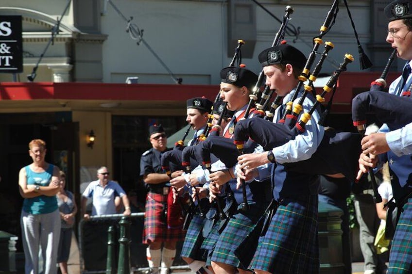 Een groep doedelzakspelers in kilts treedt buiten op. 3