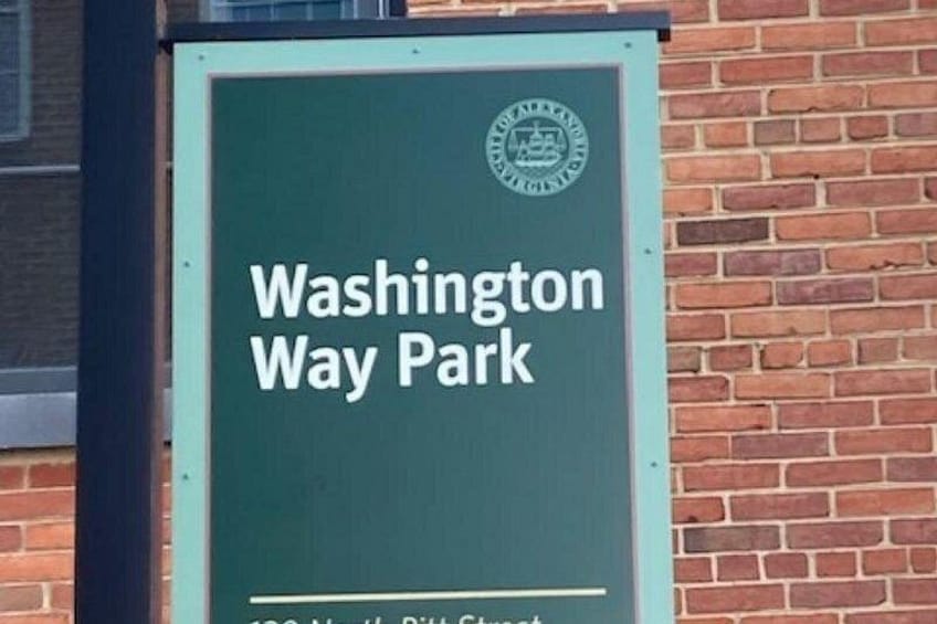 En grön skylt med texten ”Washington Way Park”, som är fäst på en tegelvägg. 3
