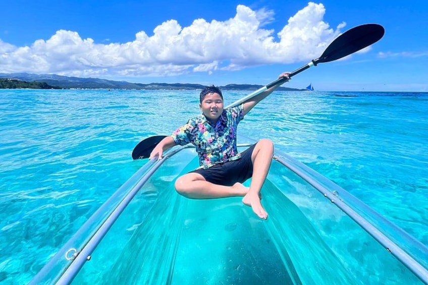 Una persona fa kayak su acque turchesi cristalline, con un'isola e montagne in lontananza. 1