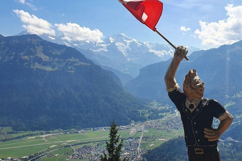 Eine Statue einer Person, die eine Flagge hält, mit einer gebirgigen Landschaft im Hintergrund. 4