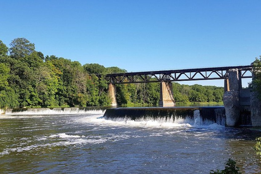 Un puente sobre un río con agua corriendo debajo, rodeado de árboles. 2