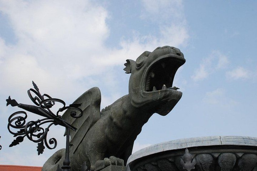 A stone sculpture of a roaring creature with a decorative metal element. 4