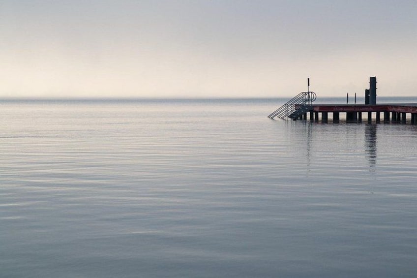 A calm sea with a pier extending into it. 2