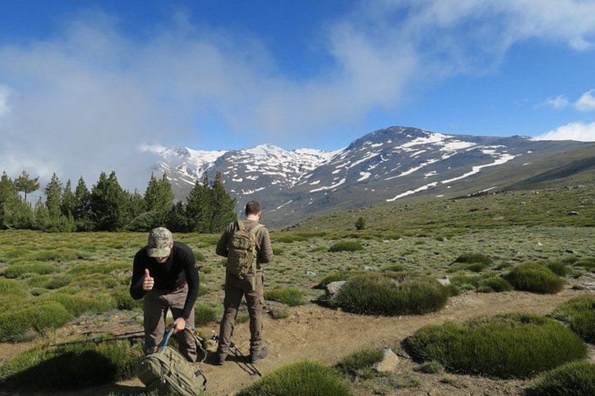 Twee personen wandelen over een grasveld, met een berg op de achtergrond. 3