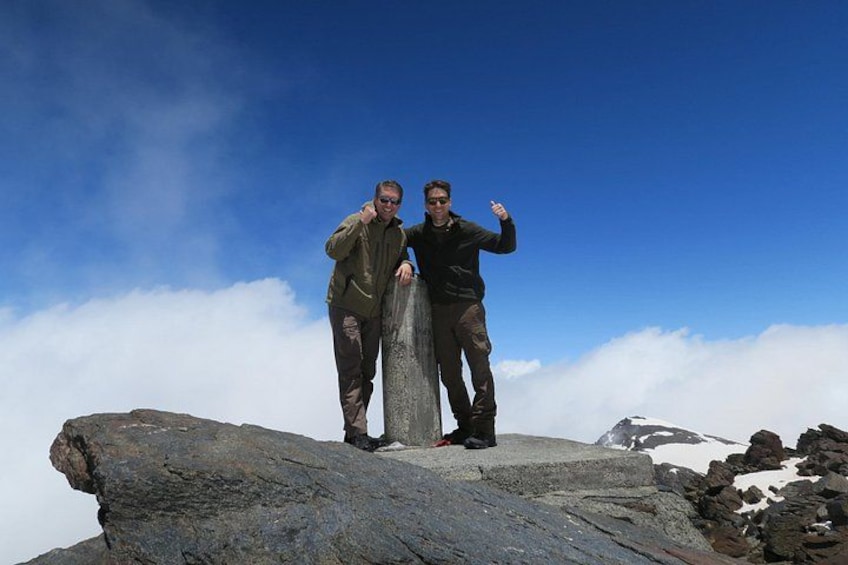 Twee personen staan op een rotsachtige bergtop met een heldere lucht. 2