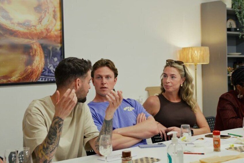 A group of people sitting at a table with a painting on the wall behind them. 4