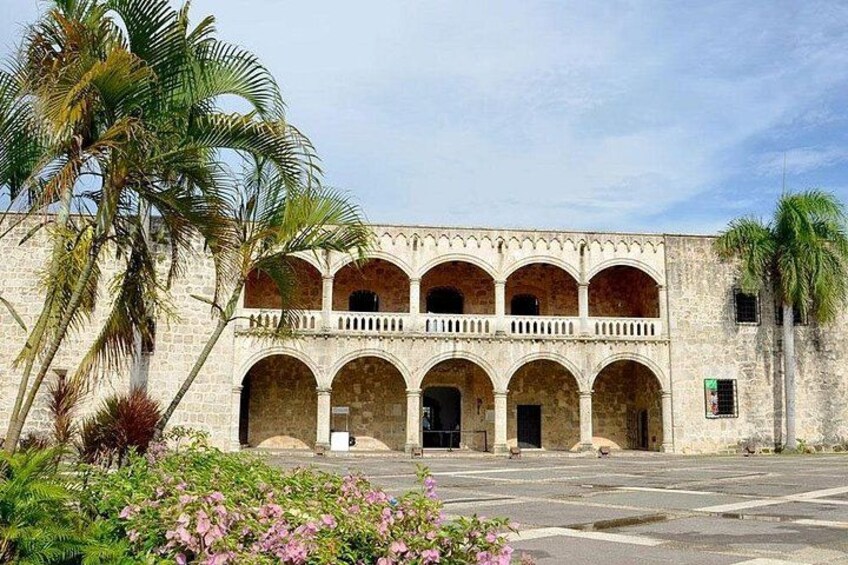 A historic building with a courtyard, palm trees, and a clear sky. 3
