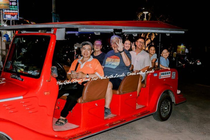 Ett rött fordon med passagerare, en skylt med texten ”Matrundtur på Phu Quoc” och en QR-kod. 2