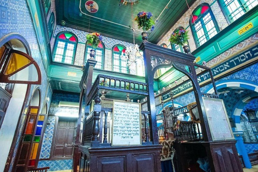 En synagogas interiör med utsmyckade dekorationer, en Torah-rulla och hebreiska inskriptioner på väggarna. 3