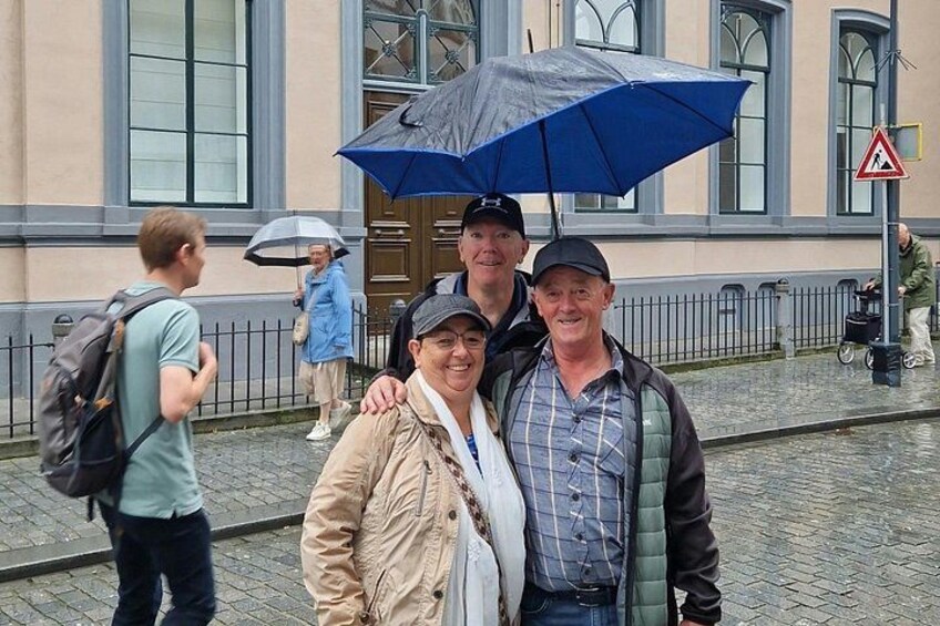 Eine Gruppe von Menschen steht auf einem Kopfsteinpflasterweg, einige halten Regenschirme. 3