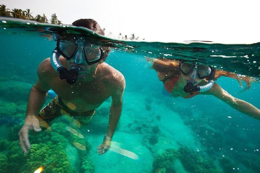 Dos personas haciendo snorkel bajo el agua, con agua cristalina y vida marina visible. 2