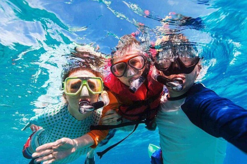 Tres personas haciendo snorkel bajo el agua. 3
