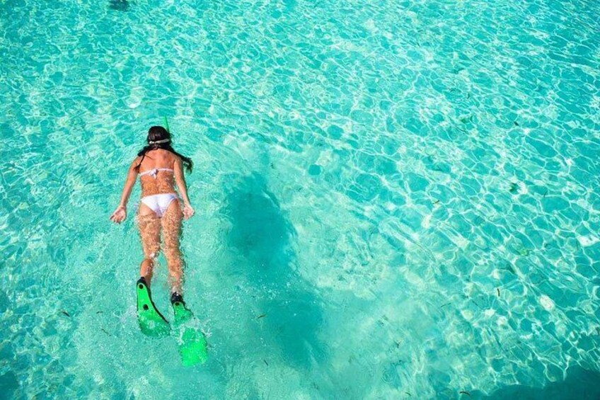 Una persona haciendo snorkel en aguas turquesas cristalinas. 5