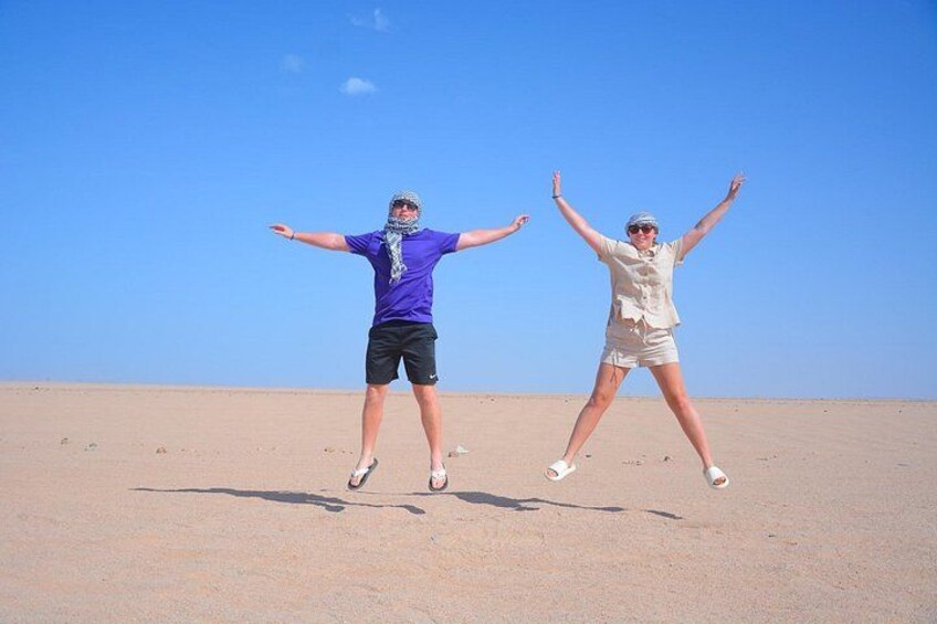 Dos personas saltando en un desierto con cielo despejado. 3
