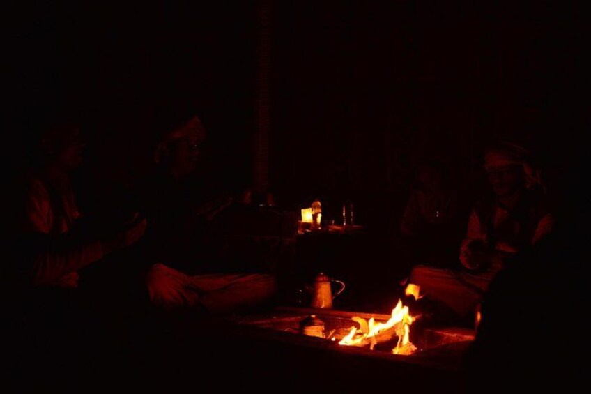Un grupo de personas sentadas alrededor de una fogata en un ambiente oscuro. 4
