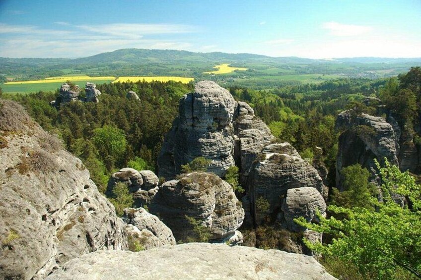 A rocky landscape with prominent rock formations and a valley with green fields. 2