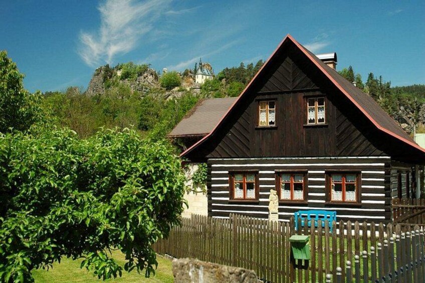 A wooden cabin with a sloped roof, surrounded by a wooden fence and lush greenery. 3