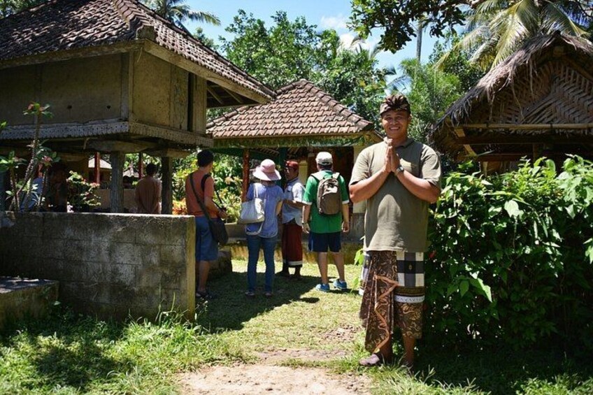 A group of people standing in a rural setting with traditional houses and lush greenery. 4