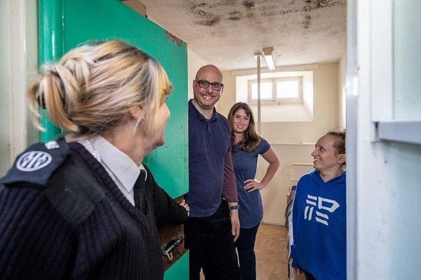 Un couloir avec un mur vert, une personne en uniforme et deux individus qui conversent. 2